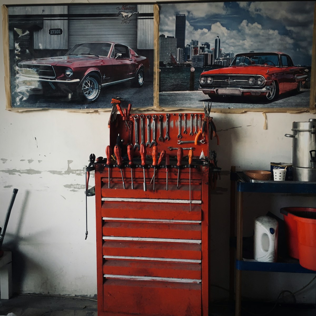 A garage with a red toolbox and a picture of a car